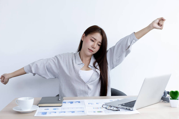 アジアのビジネスマンの女性はオフィスで残業後リラックスしています,仕事が終わった後に仕事で休んで幸せな女性,家にいます,新常態, Covid-19コロナウイルス,社会的距離,インターネット学習. - 写真・画像