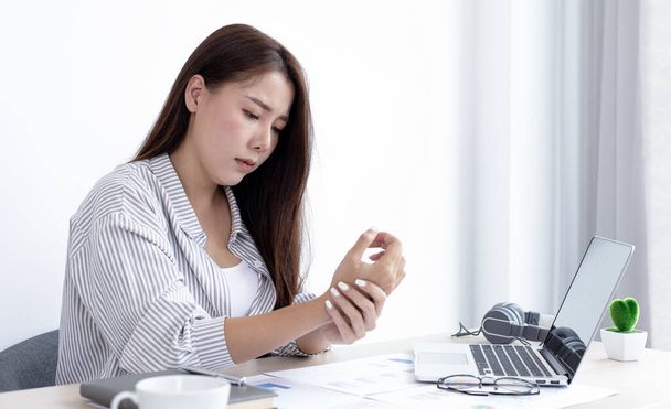 Aziatische vrouwelijke werknemer rust na haar harde werk en overwerk laat op kantoor, ontspannen van het lichaam vermoeidheid, Pols pijn. - Foto, afbeelding