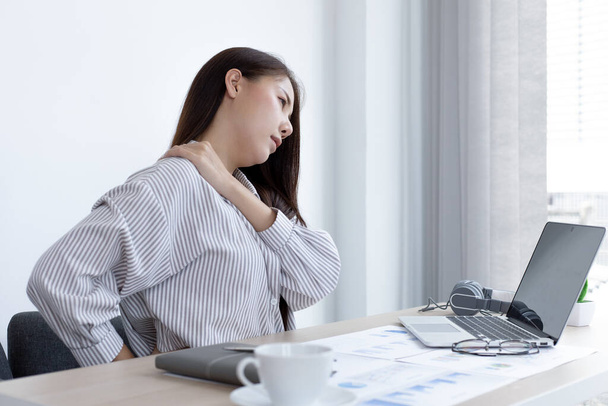 Asiatica dipendente femminile si riposa dopo il suo duro lavoro e straordinari tardi in ufficio, rilassando la fatica del corpo, dolore al polso. - Foto, immagini