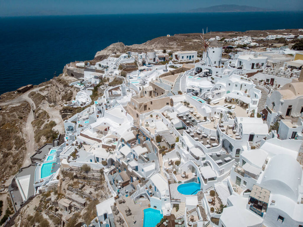 Drone view over Santorini, aerial view over the whitewashed village of Oia with luxury vacation resort with infinity pools in Santorini Greece - Photo, Image