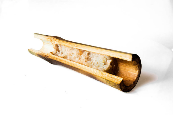 Сожженный липкий рис со сладким кокосовым молоком в бамбуковом цилиндре изолированы на белом фоне, тайская еда называют khao Я, Клиппинг путь - Фото, изображение