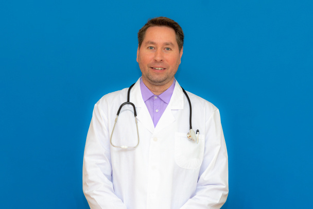 Ein Arzt mit Stethoskop steht in einer Klinik. auf hellblauem Hintergrund - Foto, Bild