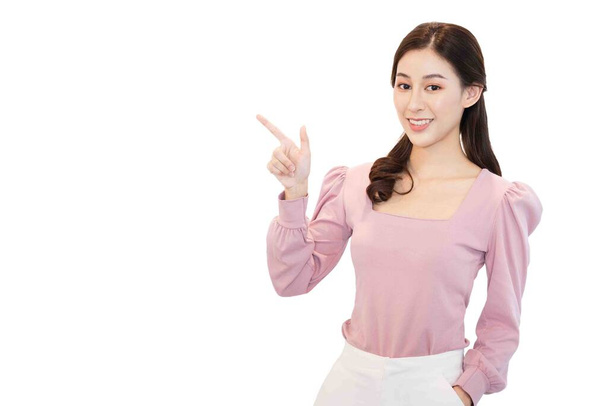 portrait of young beautiful asian business woman in casual pink t-shirt point her fingers to an empty space on the side isolated on white background,cheerful,smiling ,Charming female looking at camera - Foto, Bild