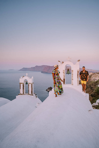 Santorini Yunanistan, Santorini Adası 'nda lüks tatilde olan genç bir çift mavi kubbe kilisesi ve beyazlatılmış Oia Santorini Yunanistan köyünün doğuşunu izliyor.  - Fotoğraf, Görsel
