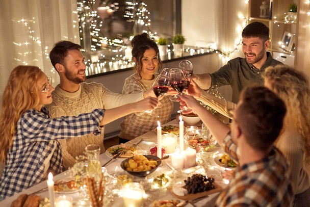 happy friends drinking red wine at christmas party - Foto, Imagen