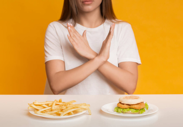 Mujer irreconocible mostrando gesto de alto, rechazando comida rápida poco saludable - Foto, Imagen