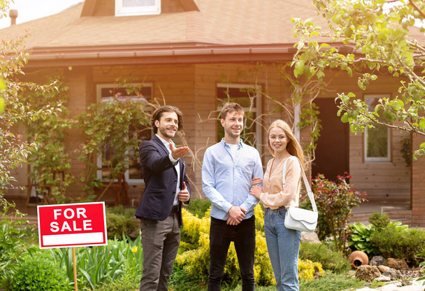 Young married couple meeting real estate manager to look at house for sale, outside - Photo, Image