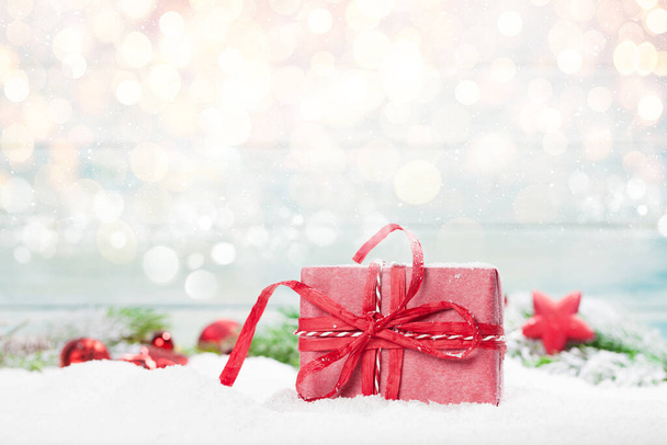Christmas greeting card with gift box in snow over blurred bokeh background and copy space for your xmas greetings - Photo, Image