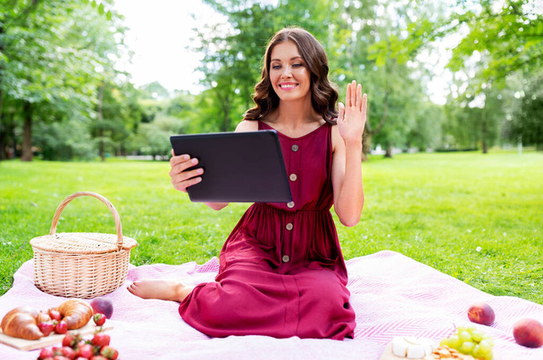 woman with tablet pc having video call at picnic - Foto, imagen