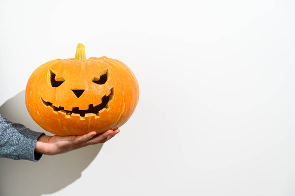 Crop Male hand holds a carved Halloween pumpkin on white background. Halloween symbol. - Photo, Image
