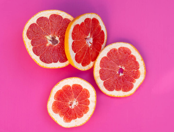 Sliced red grapefruit on a pink background - Foto, Bild
