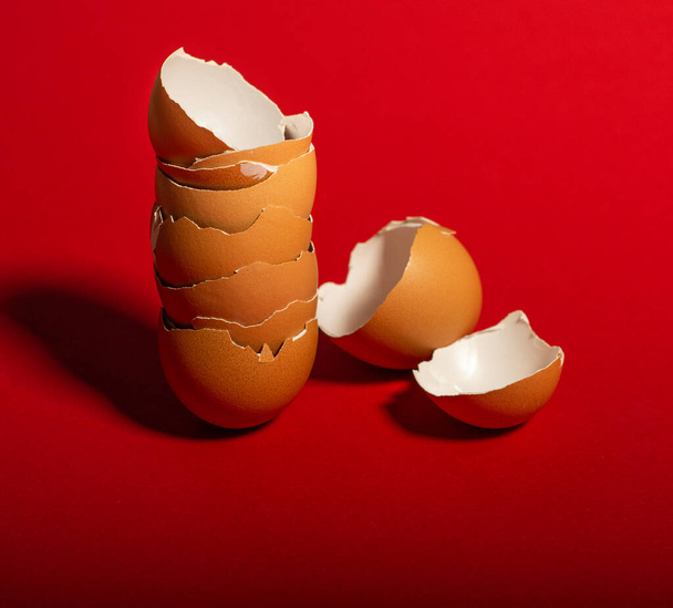 Broken brown eggshells on a red background - Photo, Image