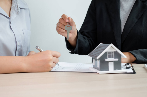 Makler übergibt dem neuen Eigentümer den Hausschlüssel nach Abschluss der Unterzeichnung gemäß Vereinbarung Anmietung eines Hauses und Kauf einer Hausversicherung. - Foto, Bild