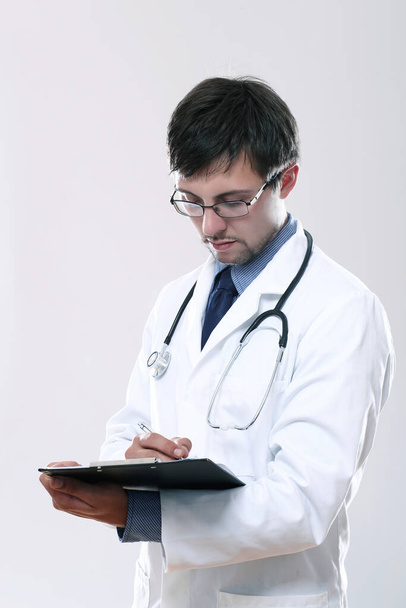 Fiatal orvos sztetoszkóppal és írótáblával szürke alapon - Fotó, kép