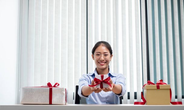 Ασιάτισσα γυναίκα κρατώντας ένα κουτί δώρου Ευτυχής να είναι ο δωρητής της έκπληξης με ενθουσιασμό, χαρά και χαμόγελα στις διακοπές, τα Χριστούγεννα, γενέθλια ή την έννοια Ημέρα του Αγίου Βαλεντίνου. - Φωτογραφία, εικόνα