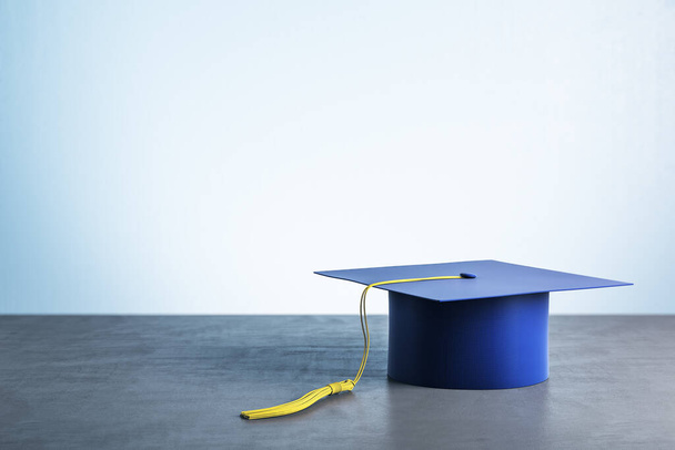 Blauwe graduatiekap op houten tafel. Bedrijfs- en onderwijsconcept. 3D-weergave - Foto, afbeelding