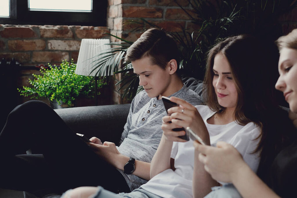 Grupo de adolescentes se divertindo e usando smartphones em casa
 - Foto, Imagem