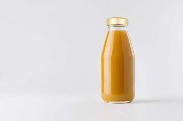Orange mango juice in glass bottle with gold cap mock up on white background with copy space, template for packaging, advertising, design product, branding. - Fotó, kép