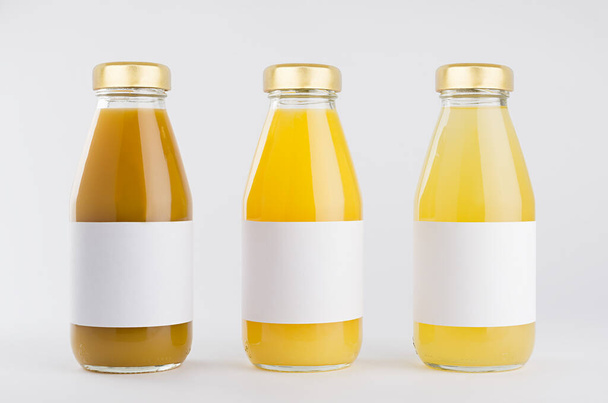 Orange, yellow fruit juices collection in glass bottles with cap, white blank labels in row mock up on white background, template for packaging, advertising, design product, branding. - Photo, image