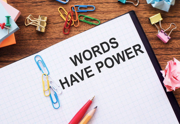 Woorden hebben kracht - inspirerend handschrift in een notitieboekje op houten tafel met pen, verfrommeld papier en paperclips, communicatie- en beïnvloedingsconcept - Foto, afbeelding