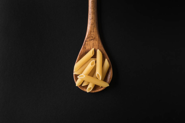 Pasta in cucchiaio di legno su fondo nero - Foto, immagini
