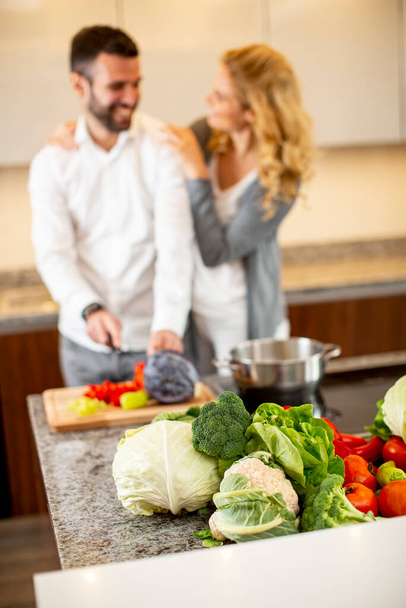 Nézd meg a fiatal férfi segít a barátnője főzés a modern konyhában - Fotó, kép