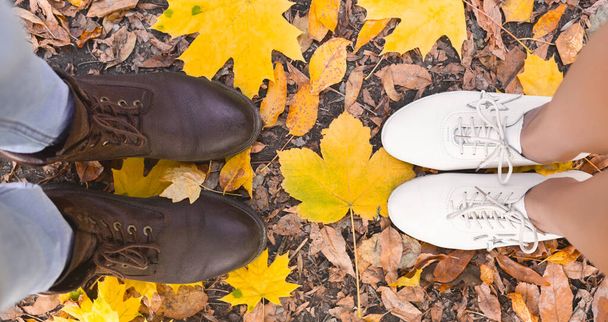Ανδρικά και γυναικεία παπούτσια πάνω σε κίτρινα φύλλα μάρπλας - Φωτογραφία, εικόνα