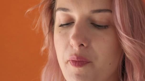 Close-up face of a young beautiful girl who is. Enjoyment of food. Pink hair. - Materiał filmowy, wideo