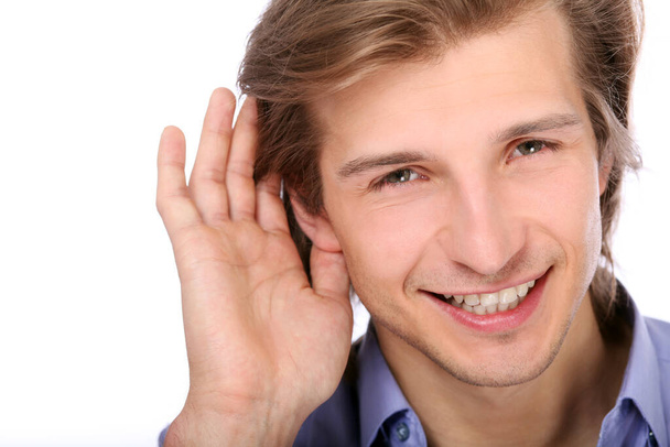Young man listening with hand on ear over white background - Fotografie, Obrázek