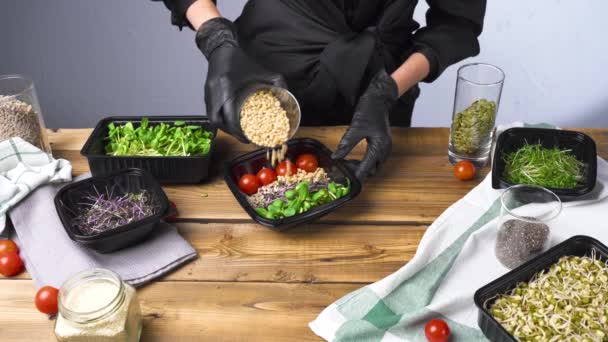 Съемка женщины в черных перчатках салат приготовления пищи с микро-зеленый и семена - Кадры, видео