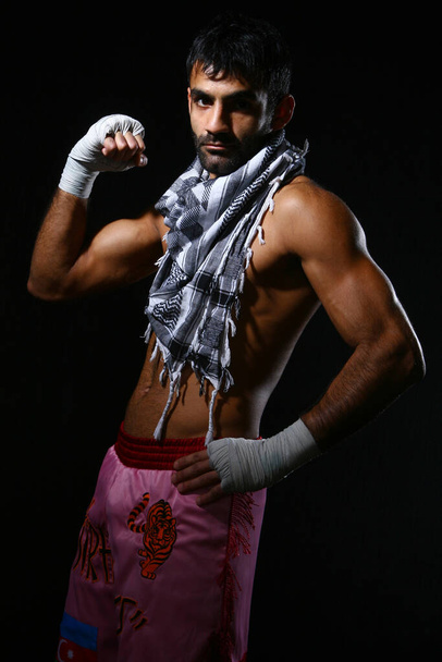 Fiatal és erős kick bokszoló sötét háttérrel - Fotó, kép
