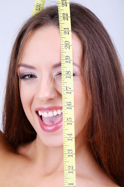 Beautiful young woman with measuring tape close up - Foto, imagen