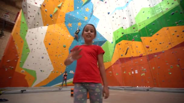 Küçük bir kız kayalık bir spor salonunda duvara tırmanıyor. - Video, Çekim