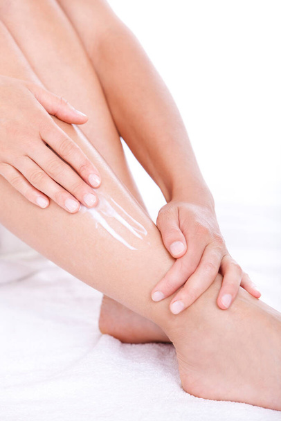 Woman applying moisturizer cream on the legs  over white background - Zdjęcie, obraz