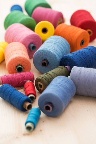 Пошив одежды. Много разноцветных нитей на столе - Фото, изображение