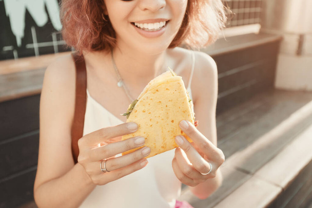 Женщина ест вкусную мексиканскую кухню кесадилья. Современная уличная еда и закуска на обед. - Фото, изображение