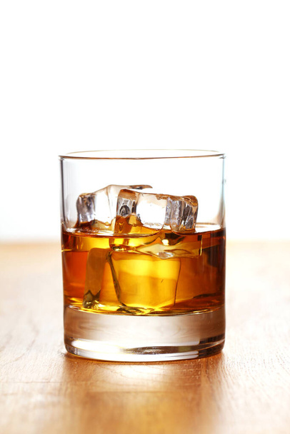 Glass of cold whiskey on wooden surface - Foto, Bild