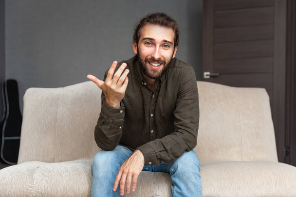 Positive young handsome man with beard talking and gesturing, looking at the camera - Fotografie, Obrázek