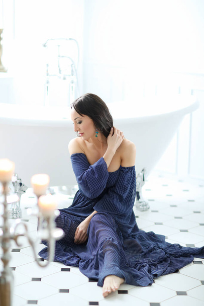 Beautiful young woman in blue dress posing at luxury bathroom - Valokuva, kuva
