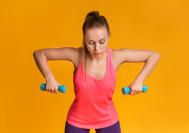 Motivoitunut kunto nainen harjoittelemassa käsipainoilla vaaleanpunaisella studiotaustalla. Harjoituskonsepti. Panoraama - Valokuva, kuva