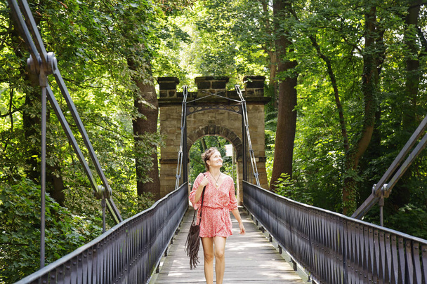 Kırmızı elbiseli kadın köprüde yürüyor, Bohemya 'daki Decin kalesinde. - Fotoğraf, Görsel