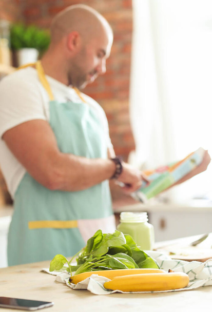 Cocina. Hombre en la cocina en delantal azul - Foto, Imagen