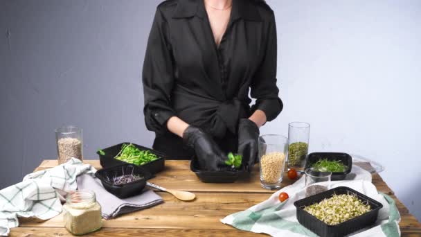 Tiro de mulher em salada de cozinha de vestido preto com micro verde e sementes - Filmagem, Vídeo