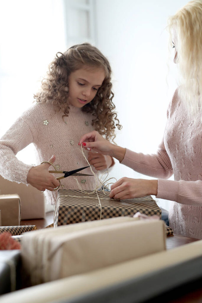 Mother and her daughter wraps gifts - Photo, image