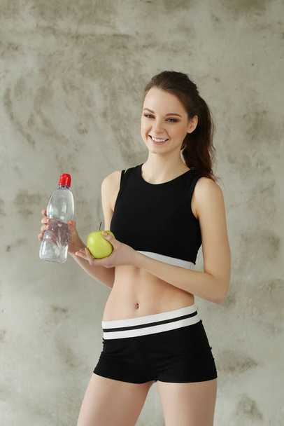 Skinny jeune femme en costume de sport posant sur fond de mur gris, sport et concept d'entraînement  - Photo, image