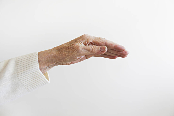 Cropped shot of elderly woman's hand over isolated white background. Wrinkled palm of unrecognizable senior lady. Close up, copy space for text. - Φωτογραφία, εικόνα