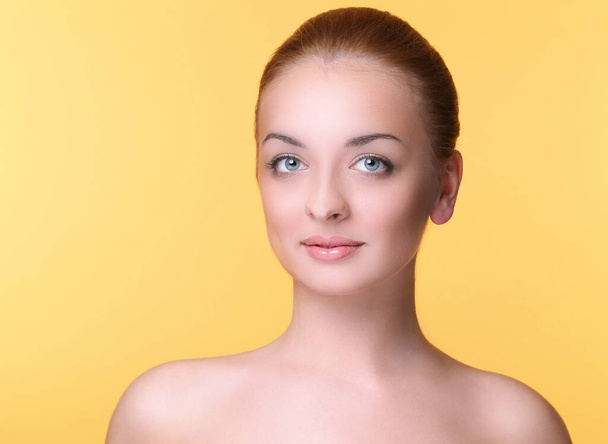 Retrato de una hermosa joven sobre un fondo amarillo - Foto, Imagen