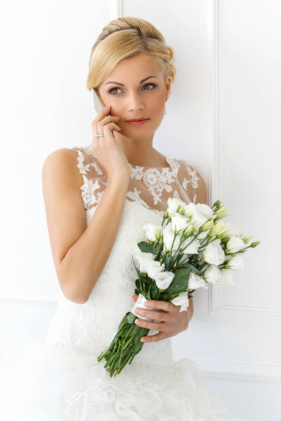Svatba. Atraktivní nevěsta s krásnou kyticí a mobilním telefonem - Fotografie, Obrázek