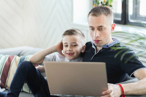 Ο μπαμπάς και ο γιος βλέποντας ταινία στο φορητό υπολογιστή στο σπίτι - Φωτογραφία, εικόνα