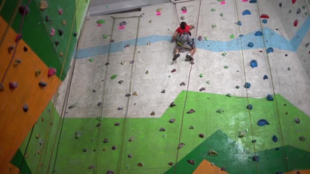 A little girl climbs up the wall in a bouldering gym - Footage, Video